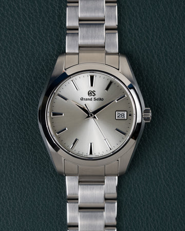 Grand Seiko Heritage Collection SBGV221 - Volledig horloge recht van boven met zilverkleurige wijzerplaat en stalen schakelband